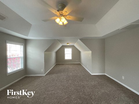 A spacious room with a carpeted floor and a ceiling fan.