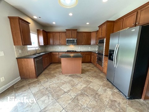 A kitchen with brown cabinets and a black refrigerator.