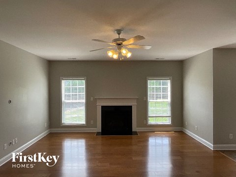 A spacious living room with a fireplace and a ceiling fan.