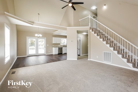 A spacious living room with a staircase leading to the upper floor.