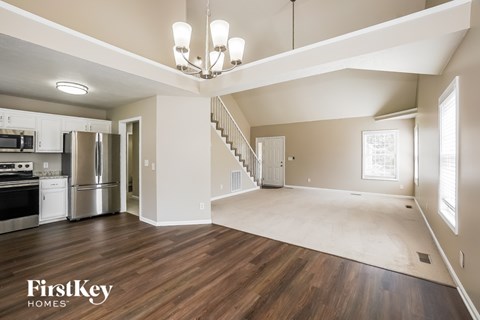 A spacious kitchen with a stainless steel refrigerator and oven, and a wooden floor.