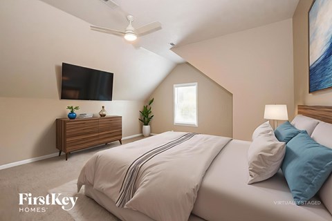 A bedroom with a bed, a ceiling fan, and a painting on the wall.
