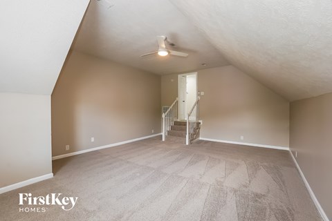 A spacious room with a staircase leading to the second floor.