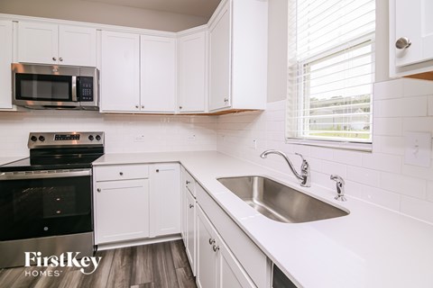 A kitchen with white cabinets and a stainless steel sink.