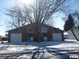 A house with a brown roof and a white garage door is surrounded by snow.