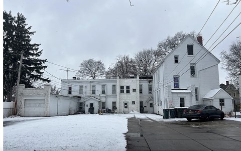 A large white house with a black car parked in front.