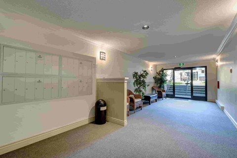 A hallway with a trash can and a door at the end.
