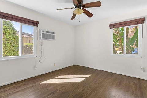 A room with a ceiling fan and a window with a view of trees.