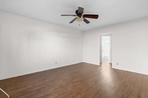 A room with a ceiling fan and wooden flooring.