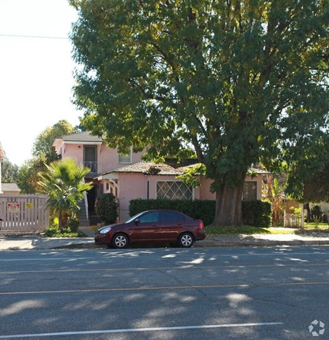 A red car is parked on the side of a street.