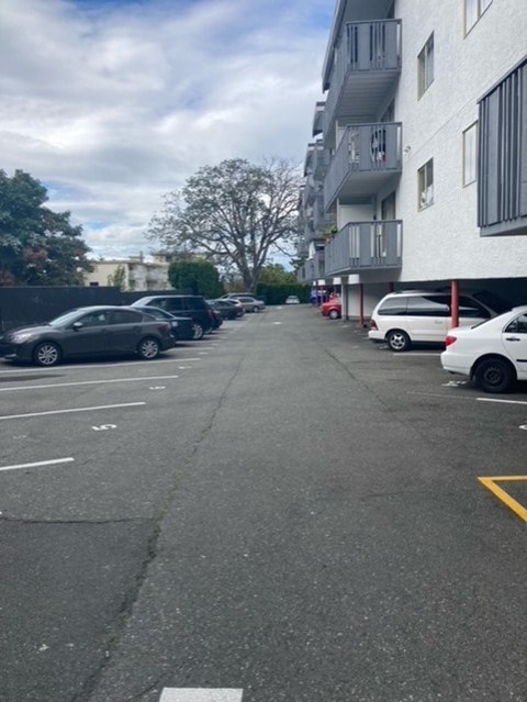 A parking lot with cars parked on the side and a building in the background.