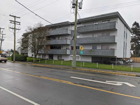 A grey building with a yellow crosswalk in front of it.