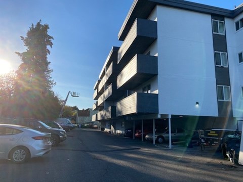 A sunny day at a parking lot with cars and a building.
