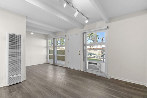 A room with a white wall and a window with blinds.