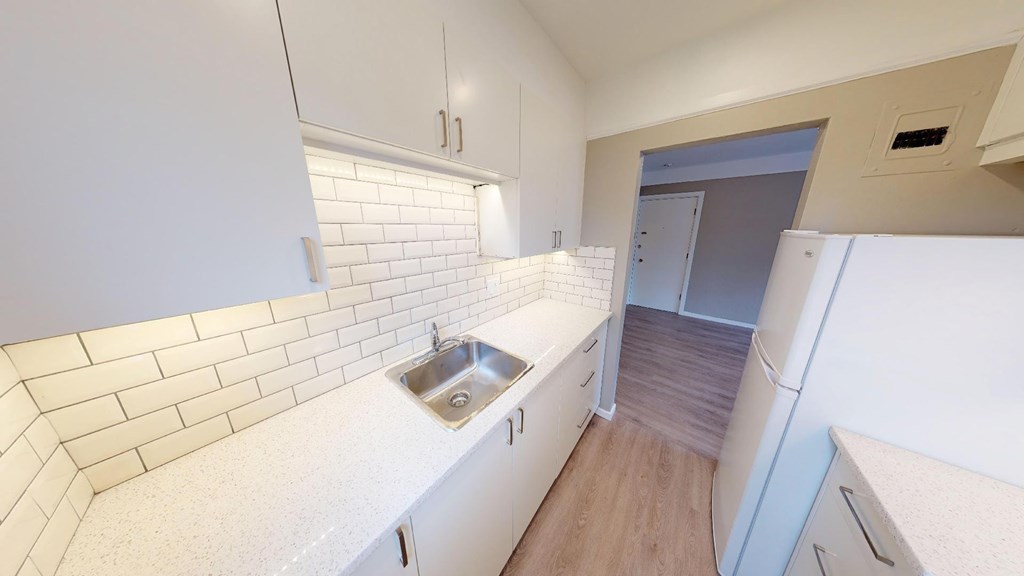 A kitchen with white cabinets and a white sink.