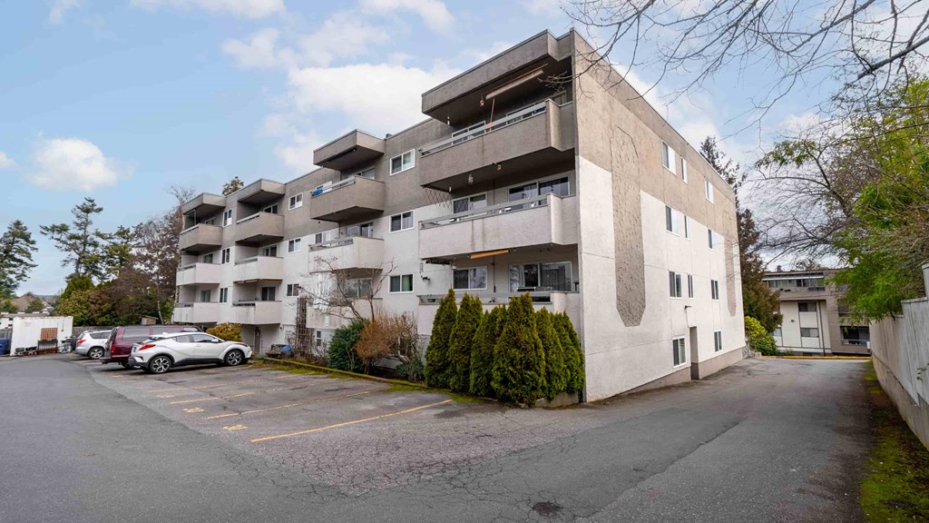 A large concrete building with a parking lot in front.