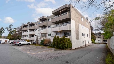 A large concrete building with a parking lot in front.