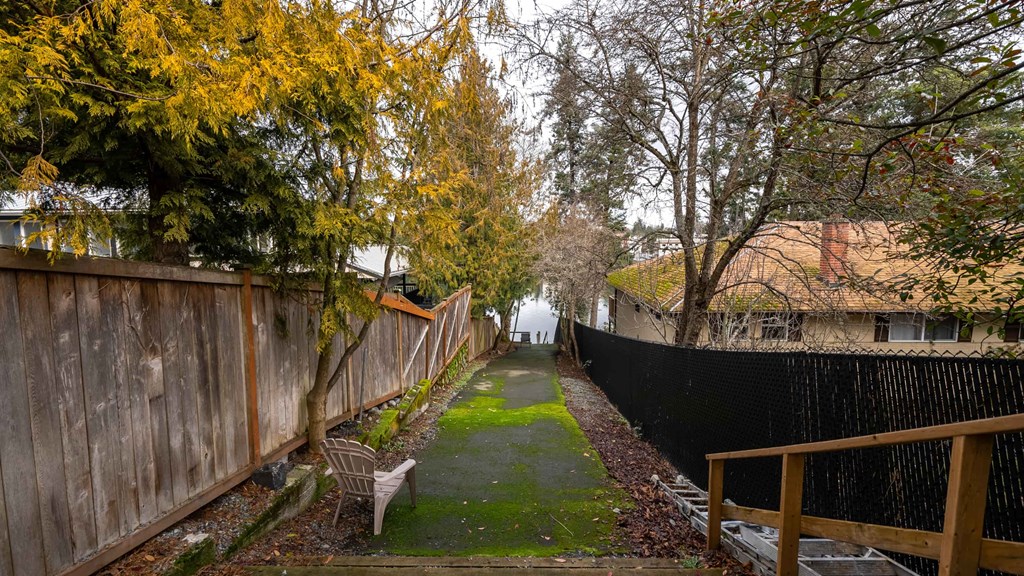 A backyard with a wooden fence and a green lawn.