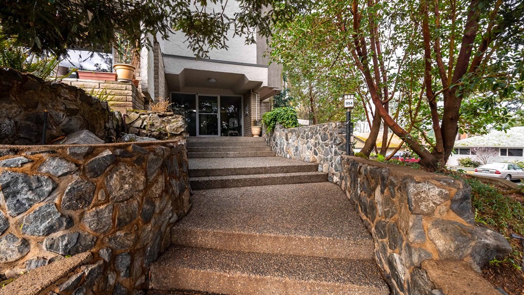 A stone wall leads to a building entrance.
