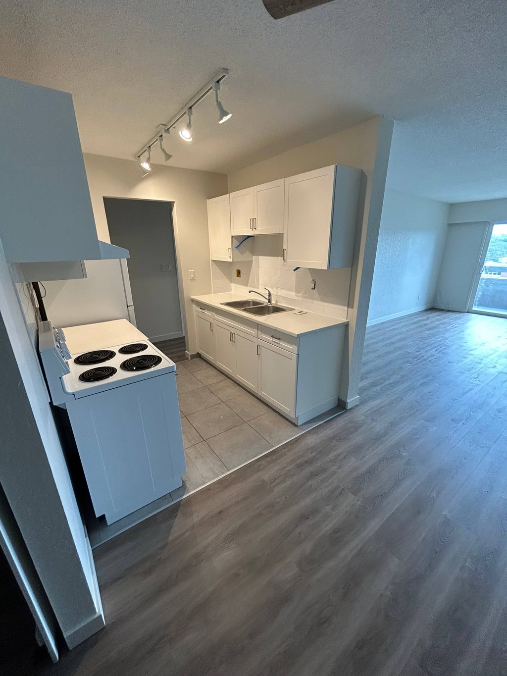A kitchen with white cabinets and a stove top oven.