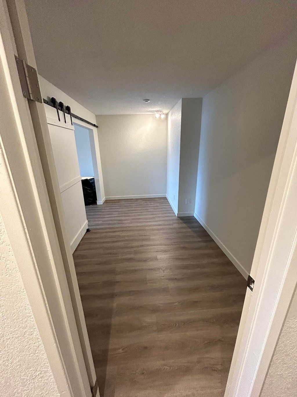 A hallway with a wooden floor and white walls.