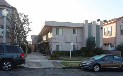 A car is parked on the street in front of a building with the number 530 on it.
