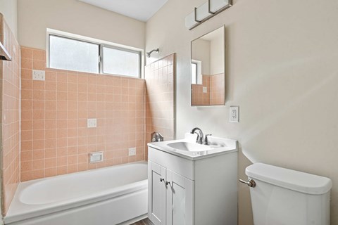 A bathroom with a white tub, sink, and vanity.