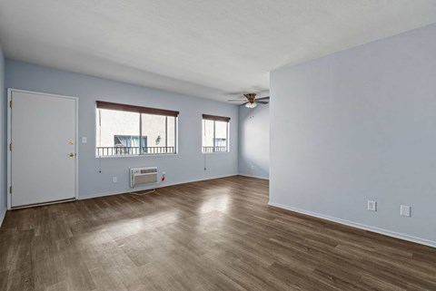A room with a white ceiling, a window with a view of a building, and a wooden floor.
