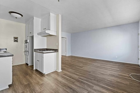 A kitchen with white cabinets and a wooden floor.