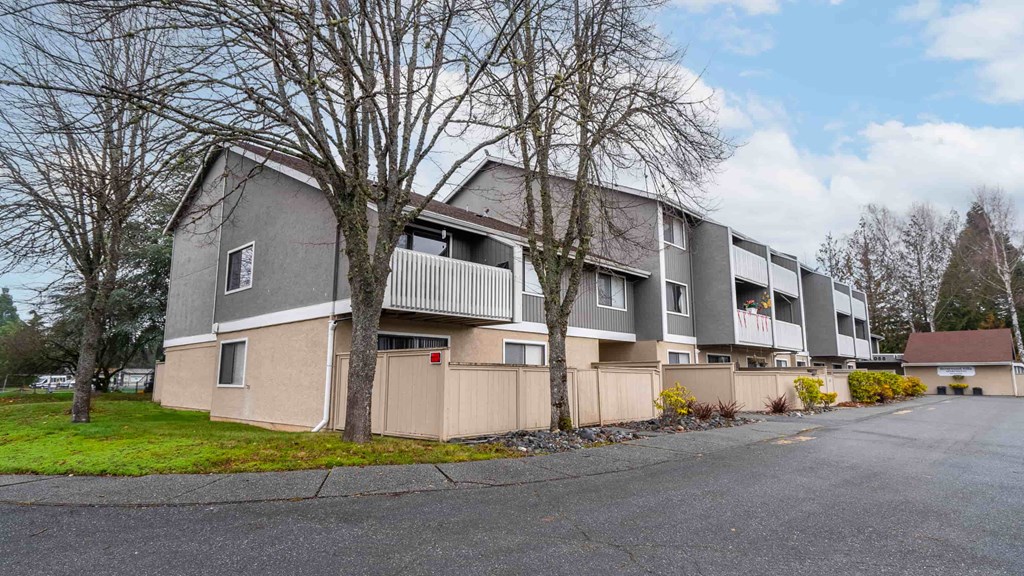 Apartment building with a grey facade and a tree in front.