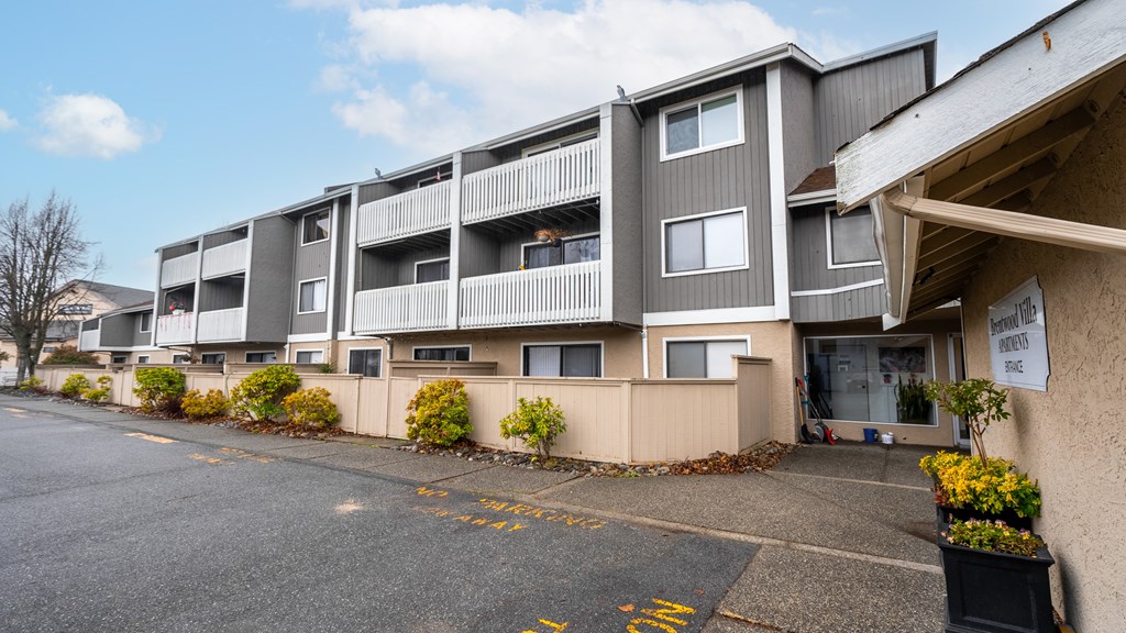 Apartment building with a parking lot in front.
