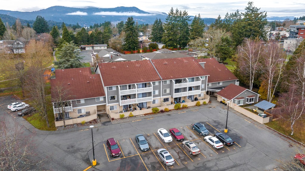 A parking lot in front of a building with a mountain in the background.