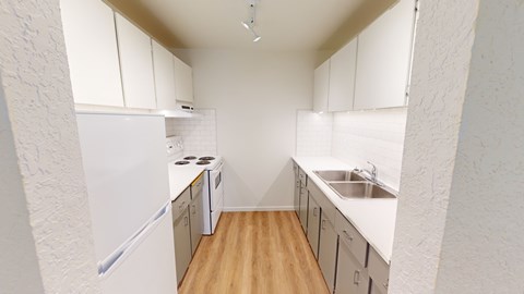 A kitchen with white cabinets and a white fridge.