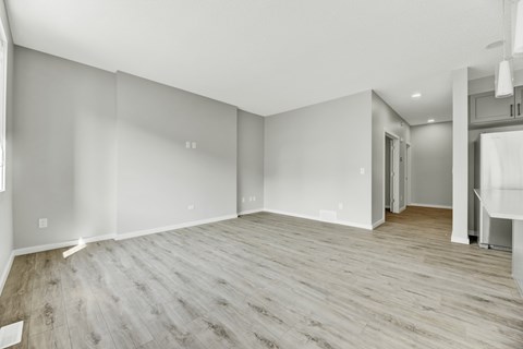 A spacious room with wooden flooring and white walls.