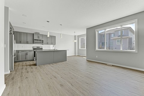 A spacious kitchen with wooden flooring and a large window.