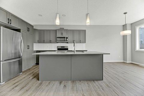 A kitchen with a refrigerator, microwave, and oven.