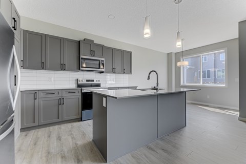 A kitchen with a white counter top and grey cabinets.