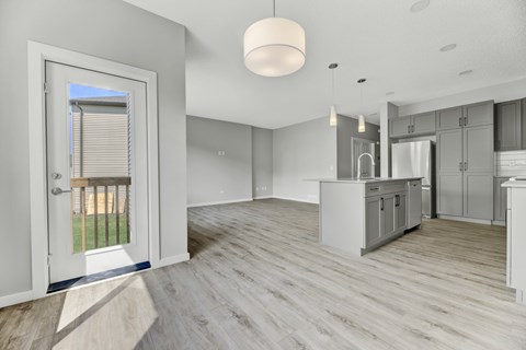 A modern kitchen with a large island and a view of the backyard through the window.