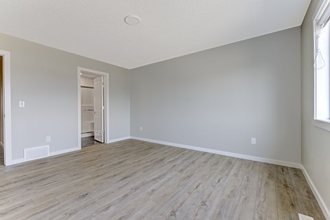 A room with wooden flooring and a doorway leading to another room.