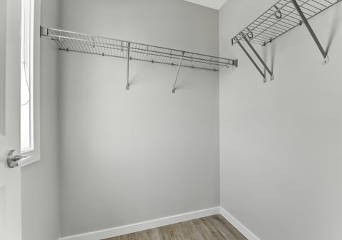 A white door is on the left of a room with a shelf and a rack.