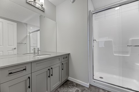 A bathroom with a sink, mirror, and shower.