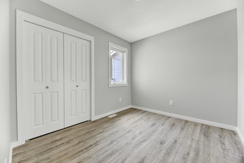 A room with a white door and a window with blinds.