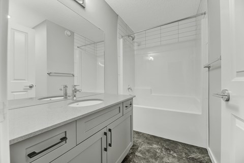 A bathroom with a sink, mirror, and bathtub.