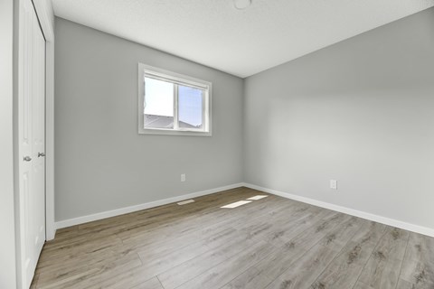 A room with a window and wooden flooring.