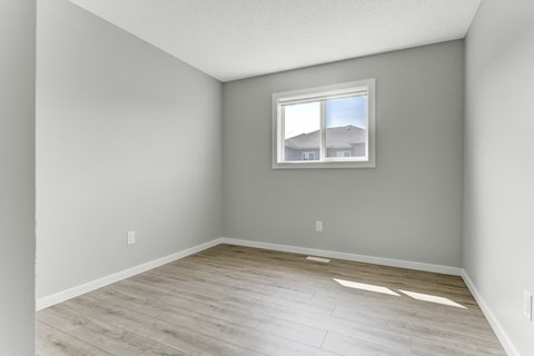A room with a window and a wooden floor.