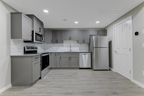 A modern kitchen with stainless steel appliances and wooden flooring.