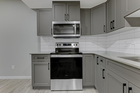 A modern kitchen with a stove top oven and microwave above it.