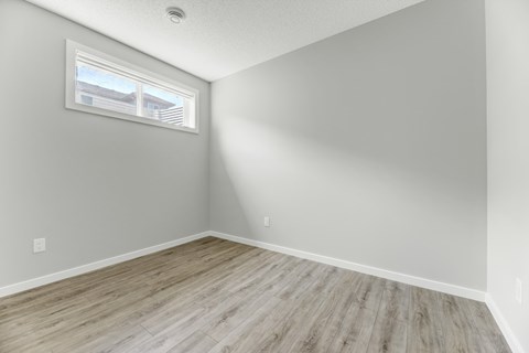 A room with a window and wooden flooring.
