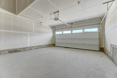 A spacious garage with a closed white door and a concrete floor.