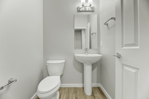 A white toilet sits next to a pedestal sink in a small bathroom.